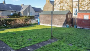 A residential area with a stone building, a grassy lawn, and a pathway. - 2 bedroom accommodation in Cellardyke, near Anstruther (Cellardyke, near Anstruther)