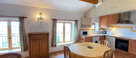 A kitchen with a dining area, wooden cabinets, a microwave, and a dishwasher.
