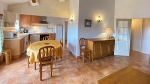 A compact kitchen with wooden cabinets, a dining table with chairs, and a small island with a lamp. - 04B9 : Beautiful T3 in the heart of lavender - pool (Brunet)