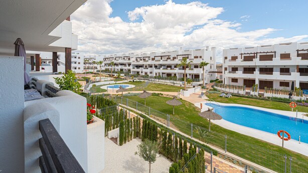 Un hotel moderno con varios edificios blancos, una piscina y un césped bien cuidado.