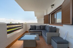 A balcony with a wicker sofa, a glass table, and a view of the landscape. - Apartamento Vamos (Mar de Pulpi) (San Juan de los terreros)