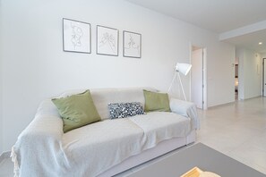 A modern living room with a white sofa, green and patterned pillows, and three line art pieces on the wall. - Apartamento Vamos (Mar de Pulpi) (San Juan de los terreros)