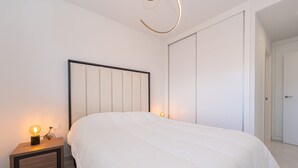 A modern bedroom with a large bed, a bedside table with a lamp, and a wardrobe. - Apartamento Vamos (Mar de Pulpi) (San Juan de los terreros)