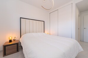 A modern bedroom with a large bed, a bedside table with a lamp, and a wardrobe. - Apartamento Vamos (Mar de Pulpi) (San Juan de los terreros)