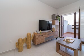 A modern living room with a wooden TV stand, a flat-screen TV, and a cactus decoration. - Apartamento Vamos (Mar de Pulpi) (San Juan de los terreros)