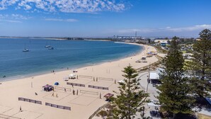 Una playa con canchas de voleibol, una orilla arenosa y barcos en el agua.