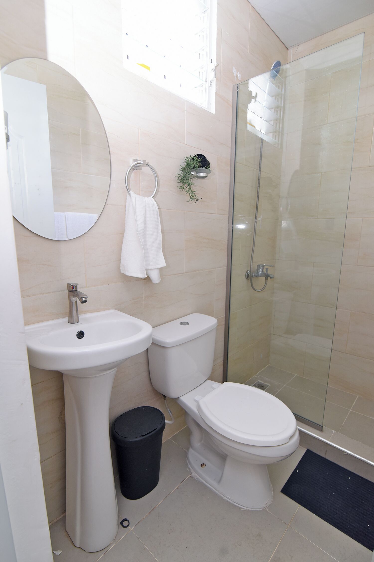 Baño con lavabo, inodoro y ducha con mampara de vidrio.