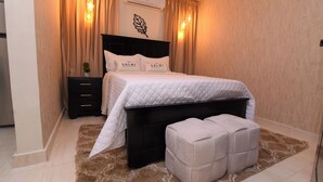 Un dormitorio con cama, mesita de noche, aire acondicionado en la pared y ventana con cortinas.