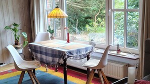 A room with a table, two chairs, a radiator, and a window with curtains. - Green pearl vacation apartment (Nenndorf)