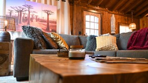 A cozy living room with a wooden ceiling, a large painting of a savannah, and a rustic stone sculpture.