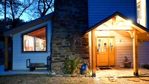 A stone house with a wooden porch and a window with blinds.