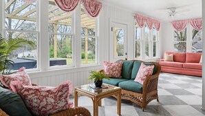 A sunroom with large windows, wicker furniture, and a checkered floor. - Historic Estate-Slps 16-Downtown-Soak Pool-Hot Tub (Murfreesboro)