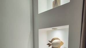 Un coin de pièce avec deux étagères fixées au mur, sur lesquelles sont exposées des sculptures de poissons décoratives.