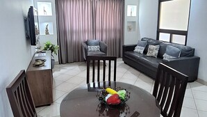Un coin repas avec une table ronde, quatre chaises et un ventilateur de plafond.