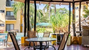 Un espace extérieur abrité comprenant une piscine, des chaises longues et une table.
