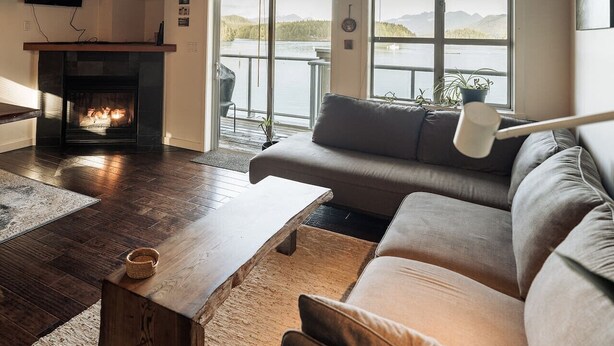 A cozy living room with a fireplace, a sofa, and a coffee table. - Island Vista - Waterfront Condo (Tofino)