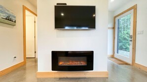 A modern living room with a flat-screen TV mounted above a fireplace. - Tidal Retreat Cabin in Tofino (Tofino)