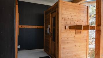 Ein Zimmer mit einer Holztür, einer schwarzen Matte am Eingang und Blick auf eine felsige Außenanlage.