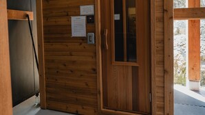 Een houten deur met een ruit, een deurmat en een klein bord aan de muur.