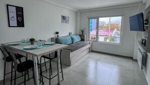 A modern kitchen with a dining area, a built-in bench, and a large window with a view. - Choconcito Suite (Ushuaia)