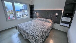 A bedroom with a bed, a window, a built-in shelf, and a view of the outside. - Choconcito Suite (Ushuaia)
