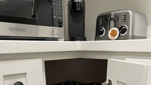 A kitchen with a microwave, coffee maker, and toaster. There are two drawers and a shelf with black trays. - Super Convenient, Cozy 2B1b Apartment, Berkeley (Berkeley)