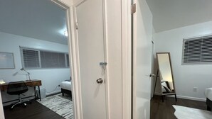 A bedroom with a bed, a desk, a chair, a mirror, and a door. - Super Convenient, Cozy 2B1b Apartment, Berkeley (Berkeley)