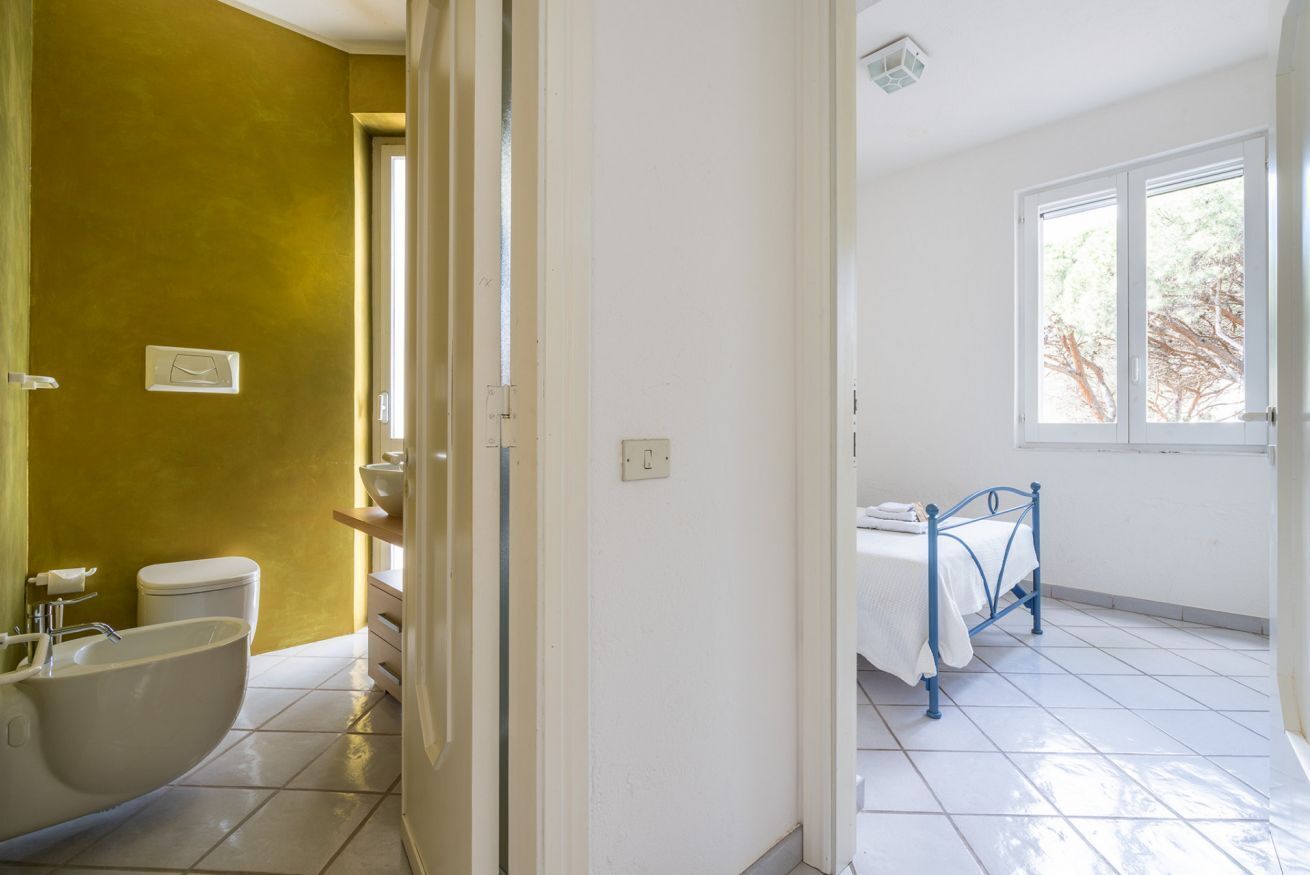 Ein Badezimmer mit Badewanne, Toilette und Waschbecken; ein Schlafzimmer mit Bett und Fenster; und ein Flur mit einer Tür.