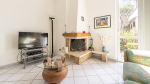 A living room with a flat-screen TV, a fireplace, a glass coffee table, and a sofa.