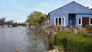 A blue house by a river with a wooden dock. - 1 bedroom accommodation in Beccles (Beccles)