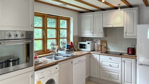 Een moderne keuken met witte kasten, roestvrijstalen apparatuur en een groot raam.