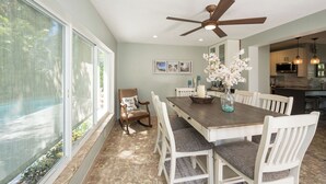 A dining area with a wooden table, white chairs, and a ceiling fan. - ISLAND SANCTUARY KEY WEST - 3 Bedroom / 2 Bathroom with Pool and Parking! (Key West)