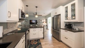 A modern kitchen with white cabinets, stainless steel appliances, and a central island. - ISLAND SANCTUARY KEY WEST - 3 Bedroom / 2 Bathroom with Pool and Parking! (Key West)