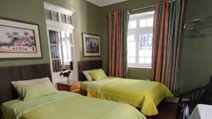 A room with two beds, a wooden floor, a table, and a chair. - Posadas Casa Real - Huancayo (Huancayo)