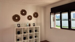A room with a white shelving unit displaying black teapots and bowls, a window with a view of a body of water, and decorative wall art. - 3-bedroom beach house in enchanting Apúlia with WiFi (Apúlia)