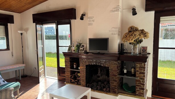 A living room with a fireplace, a television, and a bench. - 3-bedroom beach house in enchanting Apúlia with WiFi (Apúlia)
