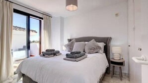 A modern bedroom with a large bed, a bedside table with a lamp, and a view of the outdoors. - Three Bedroom Townhouse 100 meters from the Beach! (Playa del Sol Villacana)