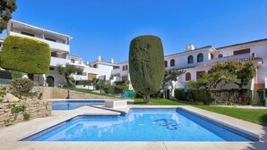 A swimming pool with a clear blue water surface, surrounded by a stone deck. There are white buildings with balconies in the background. - Three Bedroom Townhouse 100 meters from the Beach! (Playa del Sol Villacana)