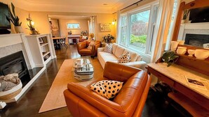 A modern living room with leather sofas, a fireplace, and a dining area. - Couple's Oasis at Horner Park, Welch Homes & Hospitality, pet friendly property. (Saanich)