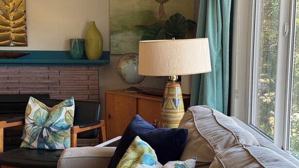 Ein Wohnzimmer mit einer Couch, Sesseln, einer Lampe und einem Kamin.