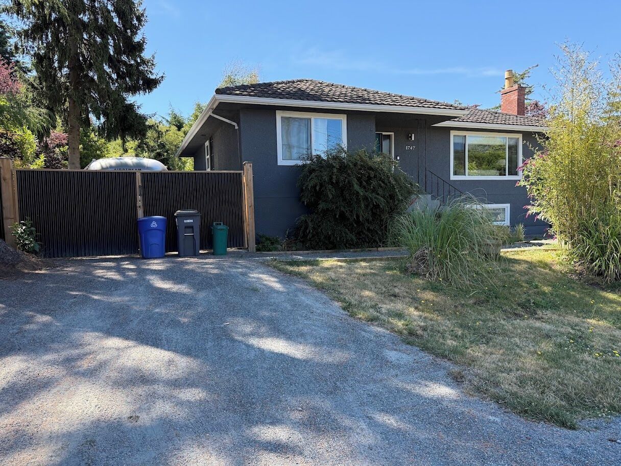 A residential house with a gravel driveway, a wooden fence, and a mailbox.