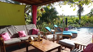 An outdoor deck with wooden furniture, including a sofa, chairs, and a table. - Spacious Beagwada villa ideal for vacations with family or friends. (Saint-François)