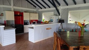 A kitchen with white cabinets, a red stove, and a sign reading "Tropical Punch Bar". - Spacious Beagwada villa ideal for vacations with family or friends. (Saint-François)