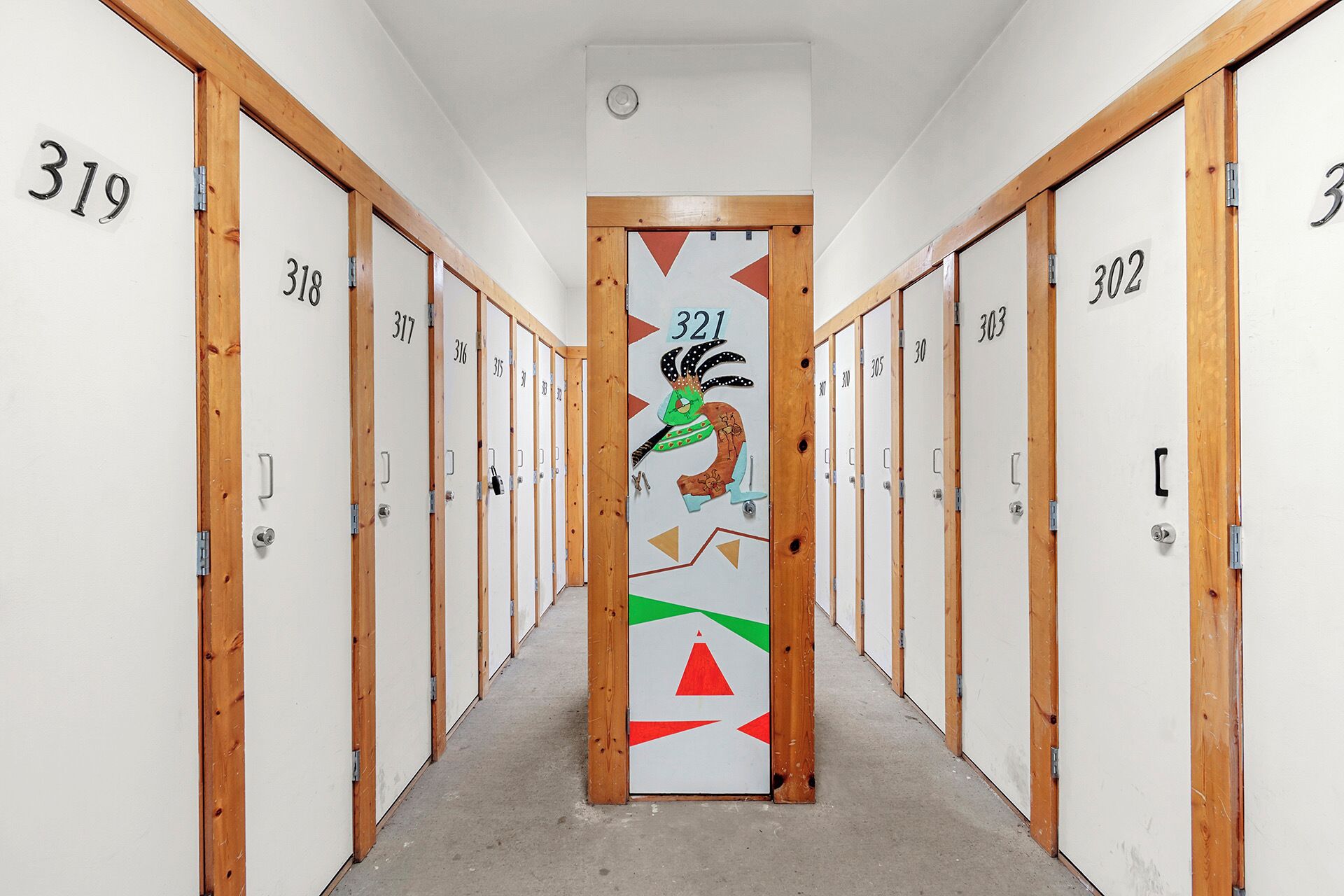 A hallway with numbered doors, each with a unique number and a small, colorful design on the door.
