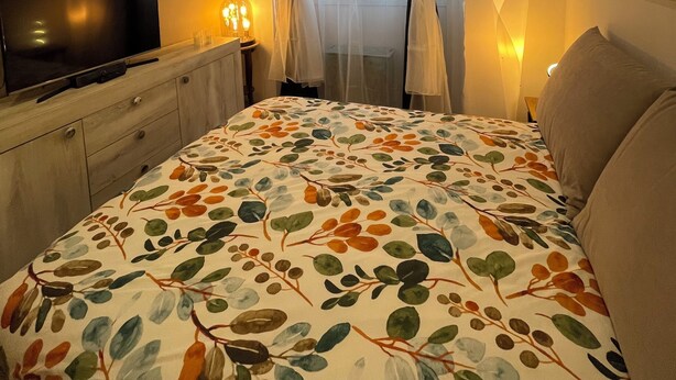 A bedroom with a bed, a TV, a dresser, and a window with curtains. - Massena street (Torino)