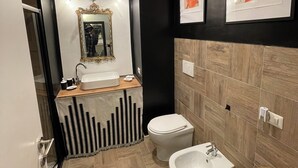 A modern bathroom with a vanity, two sinks, a bidet, and a mirror with an ornate frame. - Massena street (Torino)