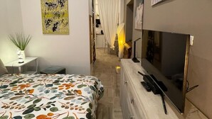 A modern hotel room with a large bed, a TV, a desk, and a painting on the wall. - Massena street (Torino)