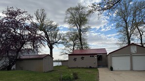 A residential area with two garages, a shed, and a grassy yard. - Finch House on Lake Osakis: Charming 2-bedroom cabin (Osakis)