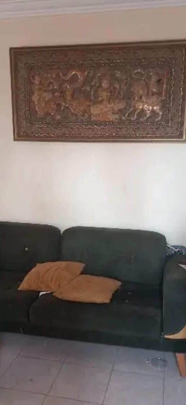 Una sala de estar con un sofá verde oscuro, un cojín marrón y un gran tapiz decorativo.