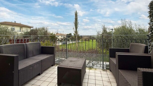 A balcony with wicker furniture, a view of a green field, and a distant building. - S346 – Sirolo, three-room apartment in a residential area (Sirolo)